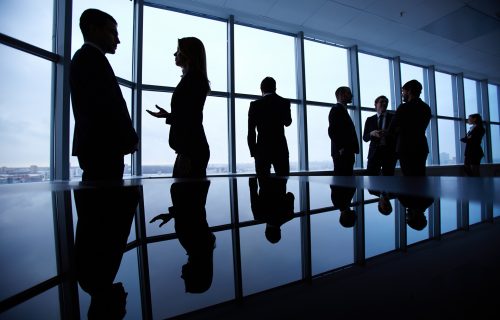 Group of colleagues standing against window in office and speaking